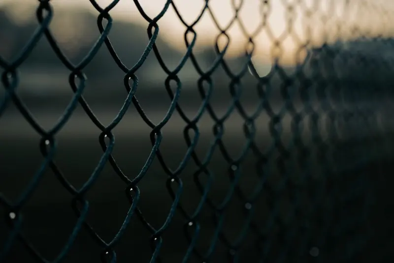 Close-up shot of a chain link fence with selective focus, creating a moody atmosphere.